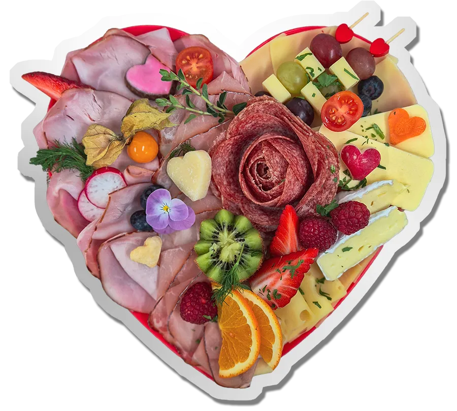 Kostbarkeiten auf einer herzförmigen Genussplatte mit feinen Wurst- und Käsespezialitäten, frischem Obst und liebevoll dekorierten Häppchen.