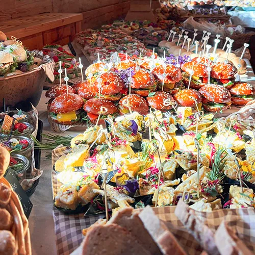 Reichhaltiges Buffet mit Burgern, Quiches und Fingerfood-Platten bei Veranstaltung – Catering von Kostbarkeiten